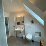 Badezimmer mit Dusche, Waschbecken und Toilette unter Dachschräge.