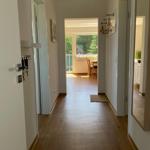 Flur mit Holzboden, Türen zu Wohn- und Schlafzimmer, Blick auf Balkon mit Gartenblick.