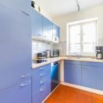Küche mit blauen Schränken, Arbeitsplatte und Fenster.