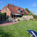 Haus mit rotem Dach, Garten mit Liegestühlen und Fahrrad.