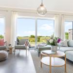 Wohnzimmer mit Sofa, Sitzgelegenheiten und Blick auf grüne Landschaft.