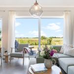 Lichter Wohnzimmer mit Sofa, Sesseln und Blick auf Felder.