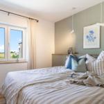 Ein Schlafzimmer mit Bett, Fenster und Wandbild.