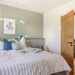 Schlafzimmer mit Bett, Wandbild und offener Tür zum Badezimmer.