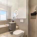 Badezimmer mit Dusche, Badewanne, Toilette und Waschbecken.