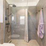 Dusche mit Duschbrause, Toilette und Handtuch an Wand