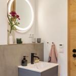 Badezimmer mit Waschbecken, Spiegel und Holztür.