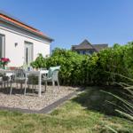 Terrasse mit Tisch und Stühlen vor weißem Haus mit rotem Dach
