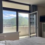 Schlafzimmer mit Balkon und Bergblick. TV und Schrank sind vorhanden.