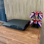 Eine PlayStation 4 und zwei Controller mit britischen Flaggenmuster stehen auf einem Holztisch.