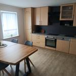 Kitchen with dining area, wooden table, cabinets, and window.