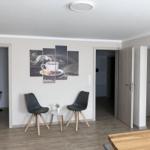 Two black chairs and a small table are in front of wall pictures.