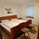 Bedroom with double bed, two chairs, and wall art of a Highland cow.