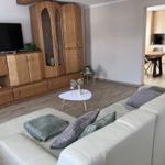 Living room with sofa, TV, and kitchen area in the background.