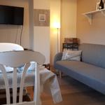 Essbereich mit Tisch und Stühlen, daneben Sofa und Fernseher an der Wand.