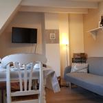 Wohn- und Essbereich mit Sofa, Esstisch und Fernseher an der Wand.