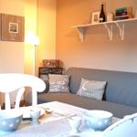 Grauer Sofa mit Kissen, Tisch mit Tassen und Schalen, Wandregal und Fernseher.