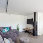 Wohnzimmer mit Sofa, Kaminofen und Fernseher.