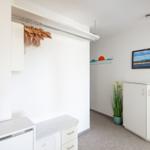 Wohnraum mit Kleiderschrank, Pflanze und Wanddekoration. Kalender an der Wand.