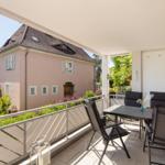 Terrasse mit Tisch und Stühlen, Blick auf ein rosa Haus und einen Turm.