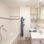 Badezimmer mit Badewanne, Duschkopf, Waschbecken und Spiegelschrank.