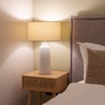 Bettkopfteil, Nachttisch und Lampe sind sichtbar. Die Lampe ist eingeschaltet.