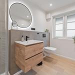 Badezimmer mit Waschbecken, Spiegel, Toilette und Dusche.