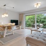 Wohn- und Essbereich mit großem Fenster, Tisch mit Stühlen und Sofa.