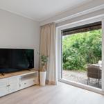Wohnzimmer mit TV, Schiebetür zum Garten und Holzboden.