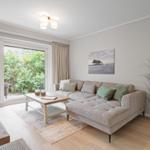 Wohnzimmer mit Sofa, Couchtisch und Glasfront zum Garten.