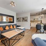 Living and dining area with sofa, coffee table, and kitchen area in the background.