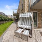 Terrace with beach chair, lawn, and balcony in background.