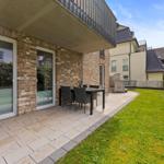 Terrace with table and chairs beside green lawn area.