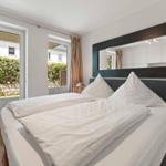 Bedroom with double bed, mirror cabinet, and windows overlooking the garden.