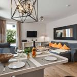 Dining area with table, chairs, and a sofa. Background: TV and mirror on the wall.