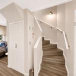 Treppe mit Handlauf führt zur oberen Etage. Nebenbei steht ein weißer Schrank.