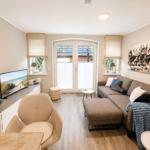 Wohnzimmer mit Sofa, Fernseher und Fenster zur Außenseite.