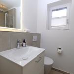 Badezimmer mit Waschbecken, Spiegel, Toilette und Dusche.