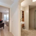 Bathroom with shower and sink. Bedroom with bed, chair, and window.