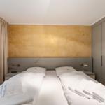 Bedroom with double bed, gold wall, and wardrobe.