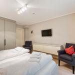 Bedroom with double bed, wardrobe, TV, and two armchairs.