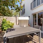 Terrace with table, chairs, and awning. Backyard with wooden fence and plants.