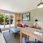 Living room with sofa, table, and view to balcony. Wall art and wooden furniture.