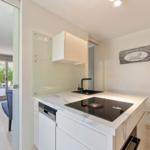 Kitchen with marble countertop, induction cooktop, and sink. Wall art and view into living area.