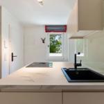 Kitchen with marble countertop, black sink, and window with view outside.