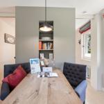 Dining area with wooden table, dark blue chairs, and built-in wall shelving.