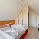 Schlafzimmer mit Doppelbett, Kleiderschrank und Sessel unter Dachschrägen.