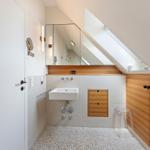 Dusche mit Spiegel, Holzwand und Fenster unter Dachschräge