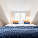 Schlafzimmer mit Dachschrägen, großem Bett und Fenster.