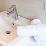 Waschbecken mit silbernem Wasserhahn und weißer Handtuchrolle